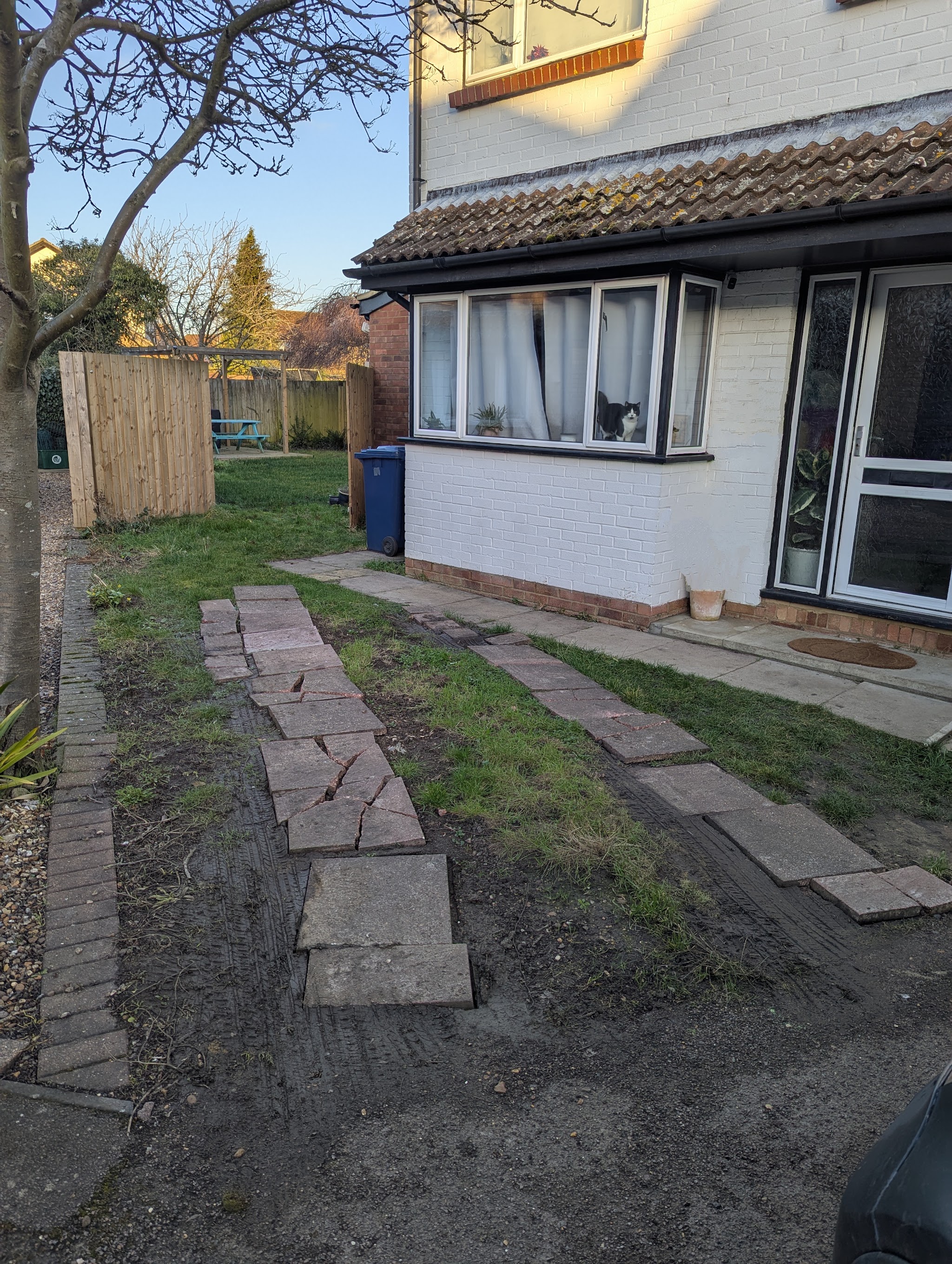 Before the work: broken paving slab tracks across a front lawn