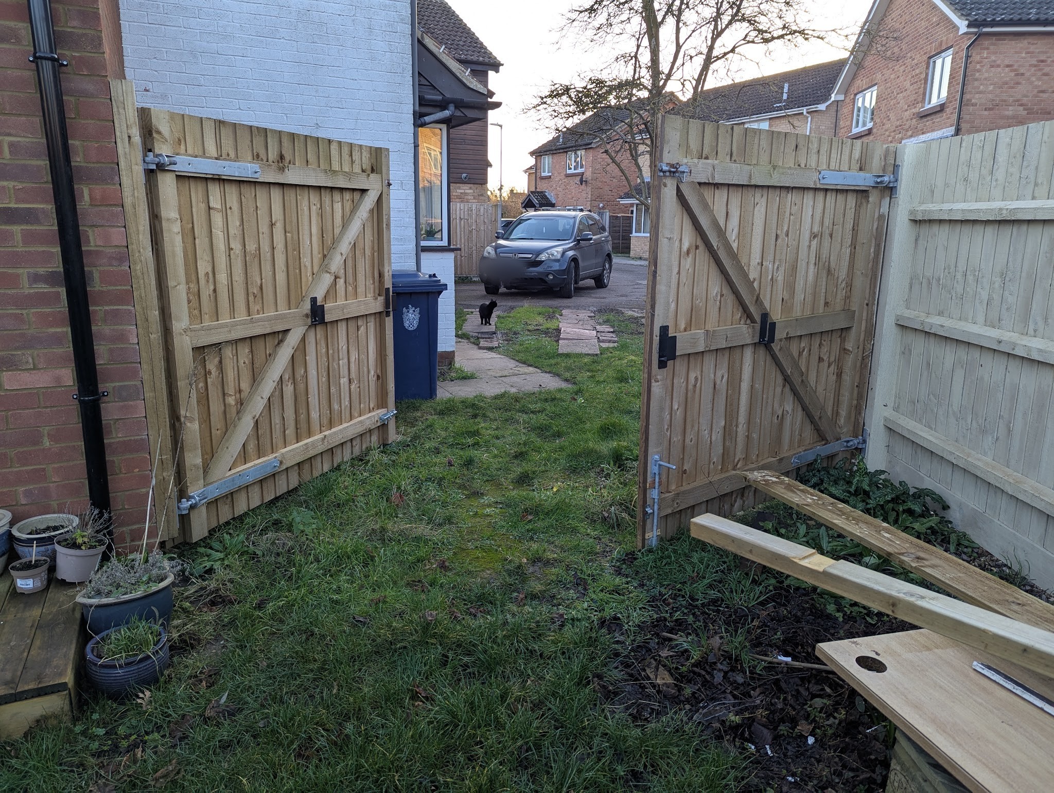 A new pair of timber side gates hung between a house and featheredge fencing